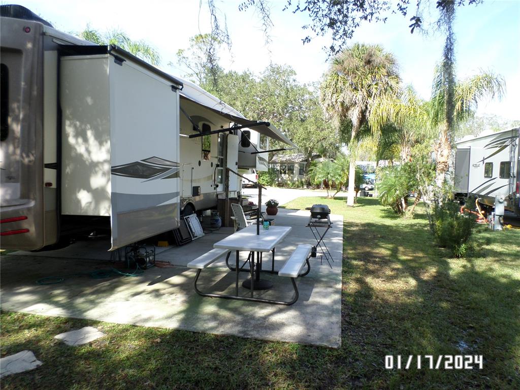 A recreational vehicle is parked on a concrete pad with a picnic table and grill — 76 NW ROAN ROAD, RIVER RANCH, FL