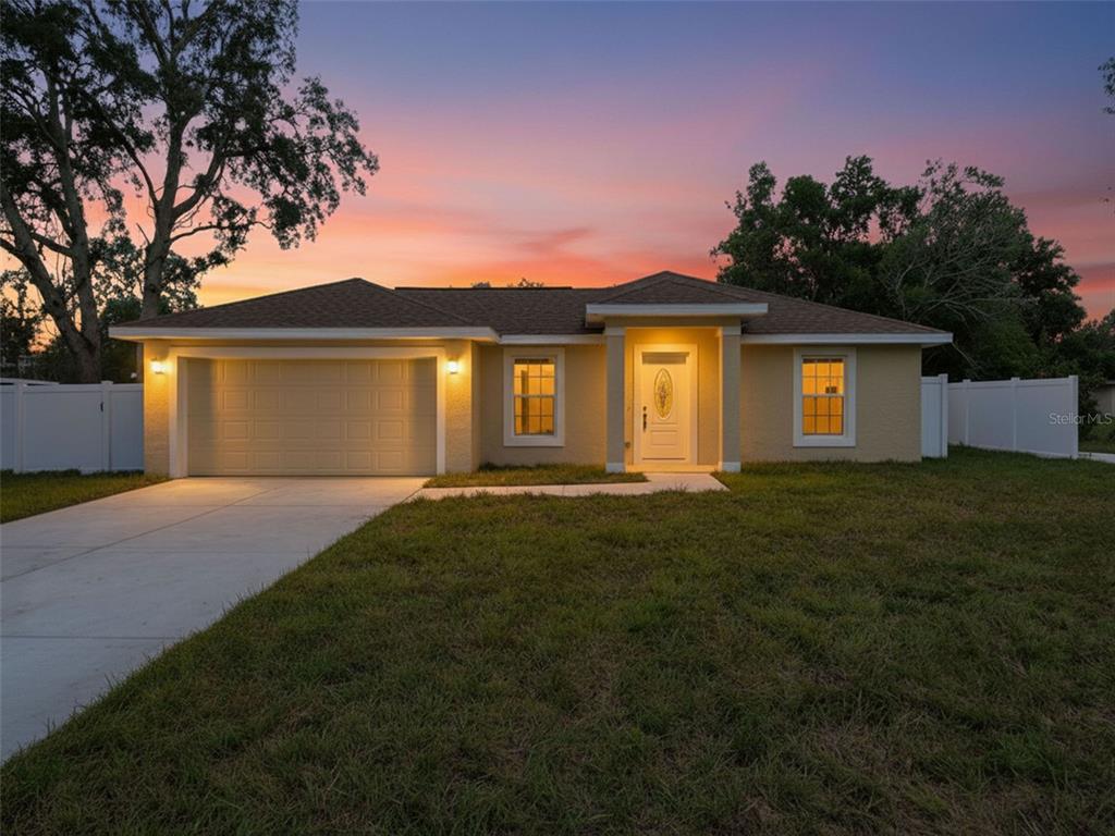 A single-story house with a tan stucco exterior, a two-car garage, and a concrete driveway — 7209 APACHE TRAIL, SPRING HILL, FL
