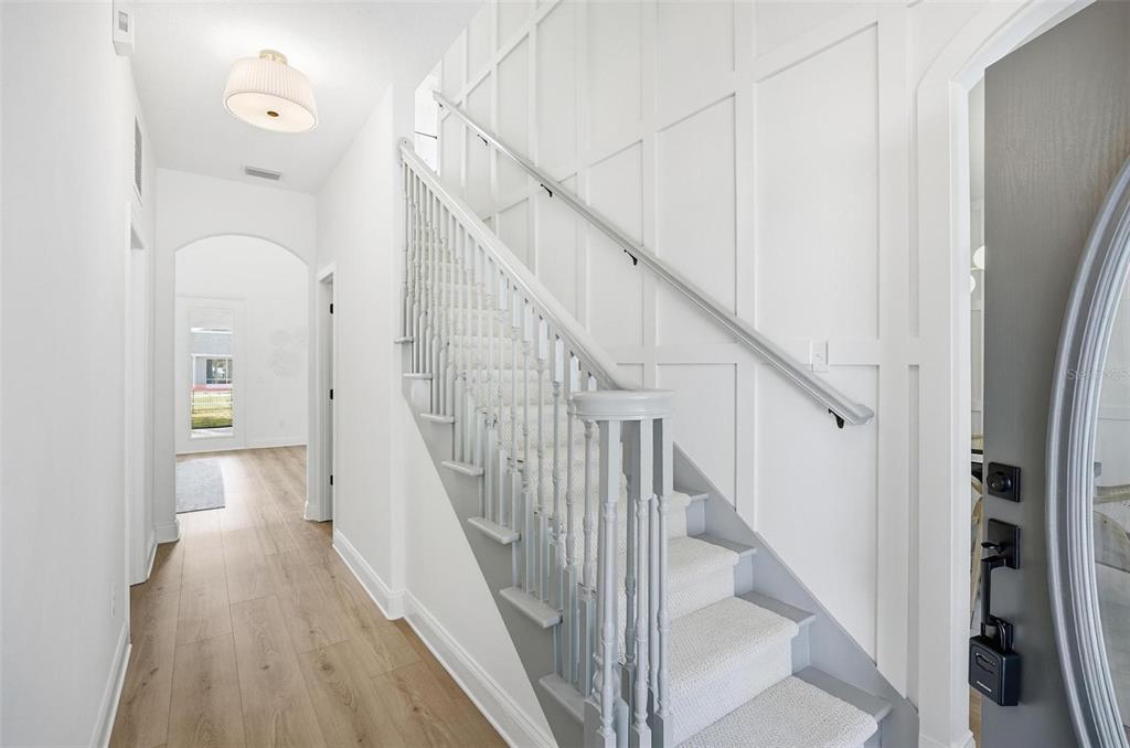 A white staircase with a gray railing and carpeted steps sits in a bright entryway — 41 OLD OAK DRIVE S, PALM COAST, FL