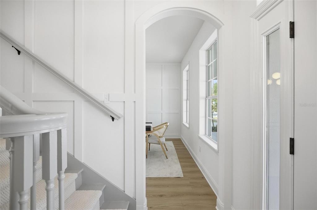 A white staircase leads to a hallway with board-and-batten walls and a glass-paneled door — 41 OLD OAK DRIVE S, PALM COAST, FL