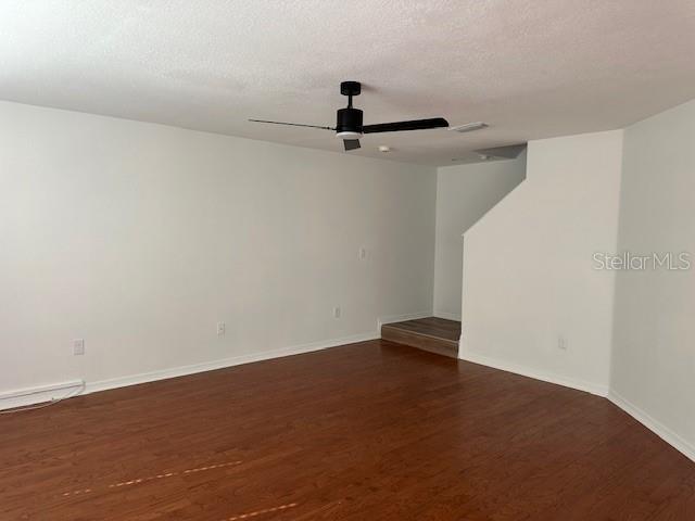 An empty room features white walls, dark wood-look flooring, and a black ceiling fan — 10931 KEYS GATE DRIVE, RIVERVIEW, FL