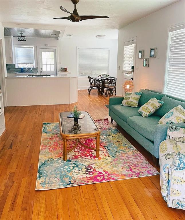 A living room with hardwood floors, a teal sofa, and a colorful area rug — 2431 7TH AVENUE N, ST PETERSBURG, FL