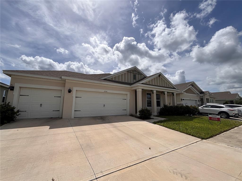 A long hallway with arched entryways and light-colored tile flooring leads toward a bright room — 6930 AUDOBON OSPREY COVE, HARMONY, FL