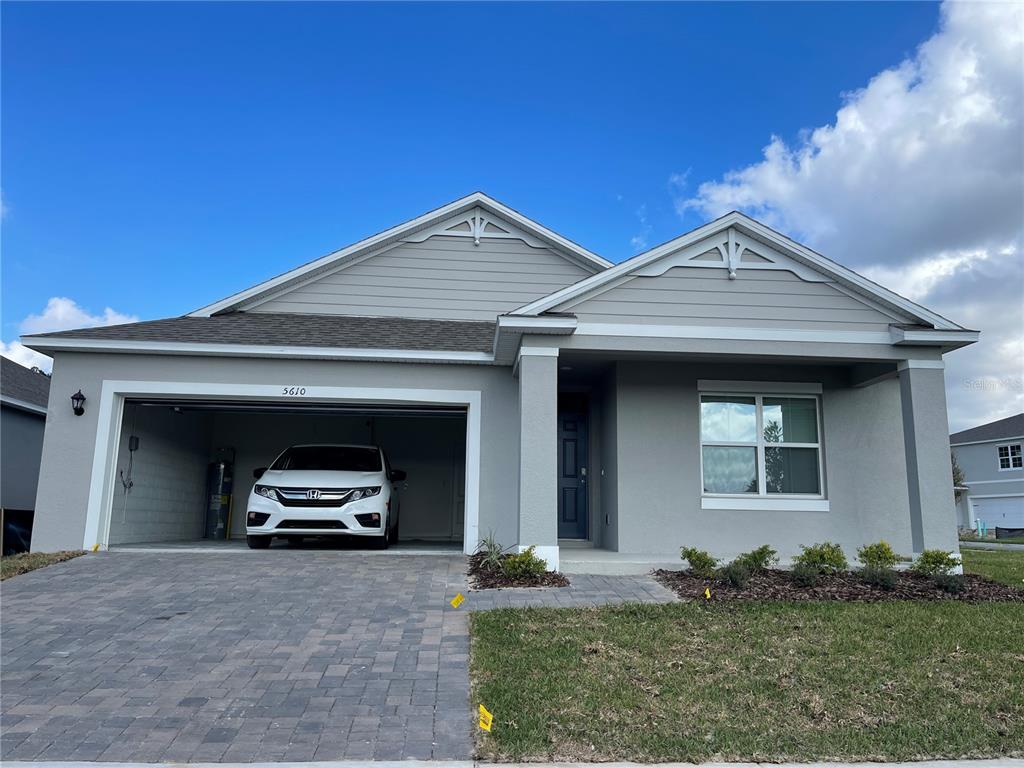 A single-story house with a gray stucco exterior, a two-car garage, and a paved driveway — 5610 GALLOPING DRIVE, APOPKA, FL