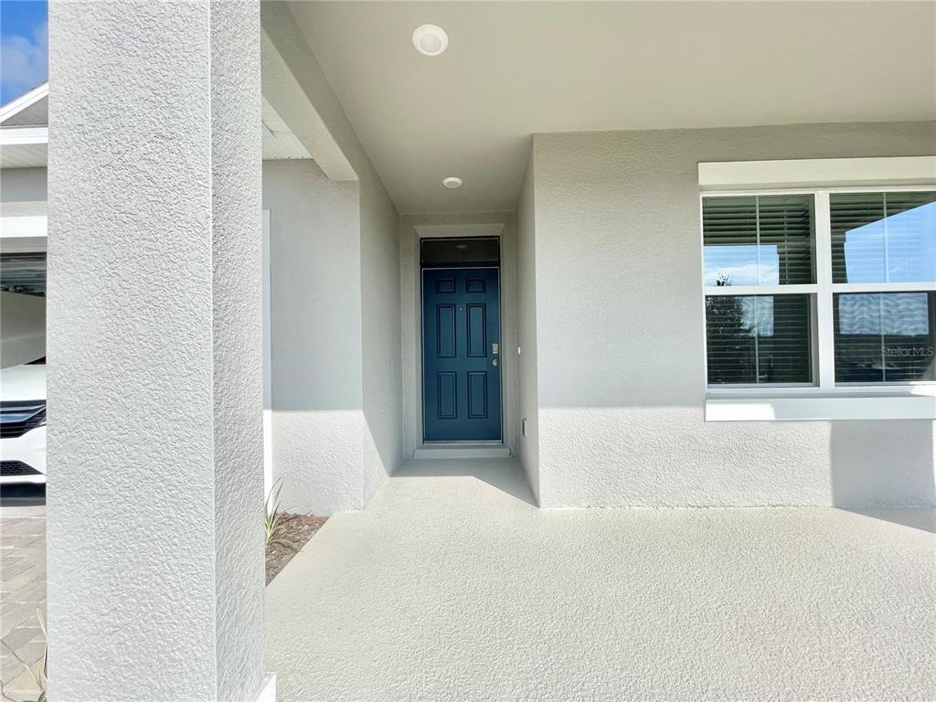 A covered entryway features a dark blue front door and a large window on the right — 5610 GALLOPING DRIVE, APOPKA, FL