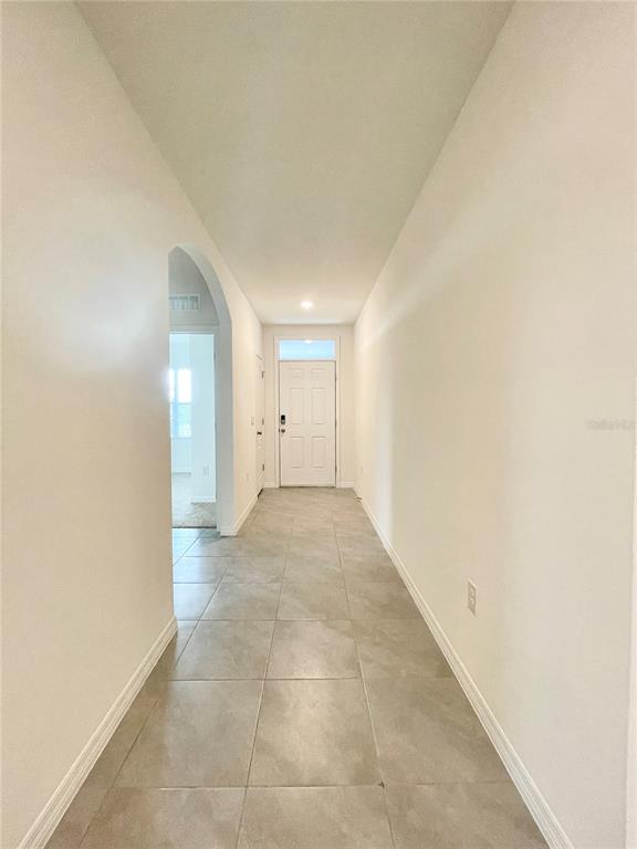A hallway with light-colored tile flooring leads to a white front door — 5610 GALLOPING DRIVE, APOPKA, FL