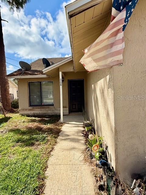 A concrete walkway leads to the front entrance of a house with an American flag — 608 E WARREN AVENUE, LONGWOOD, FL