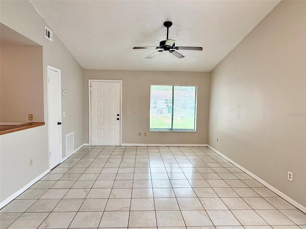 The exterior of a tan concrete block house features a sliding glass door and fence — 608 E WARREN AVENUE, LONGWOOD, FL