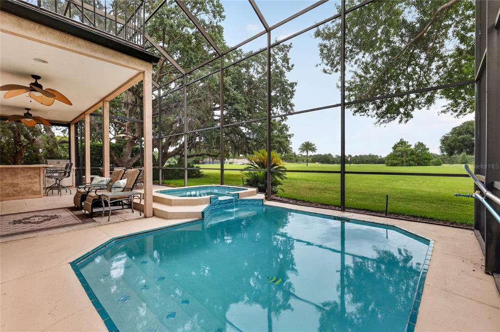 A screened-in patio features a swimming pool, a raised spa, and a view of a golf course — 1920 EDGEWATER DRIVE, MOUNT DORA, FL