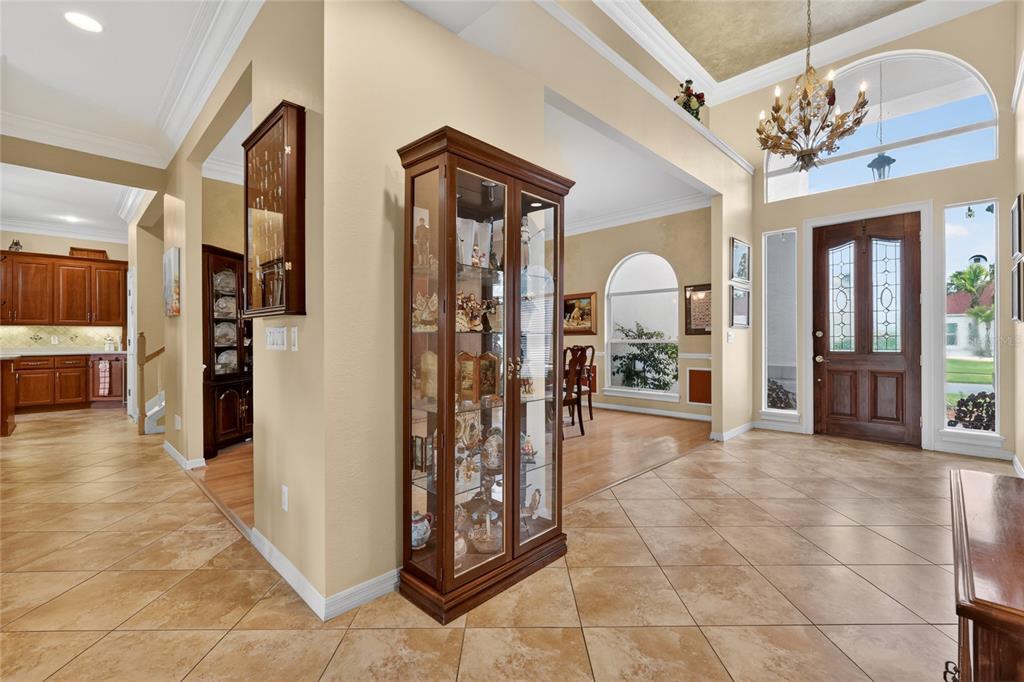 A tiled foyer features a glass display cabinet, a chandelier, and a view into the kitchen — 1920 EDGEWATER DRIVE, MOUNT DORA, FL