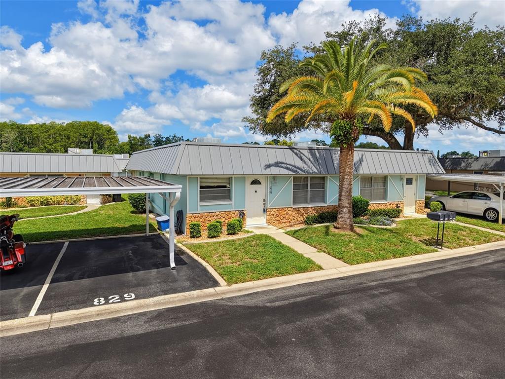 A single-story duplex with a metal roof, stone facade, and a covered carport — 11829 CARISSA LANE, NEW PORT RICHEY, FL