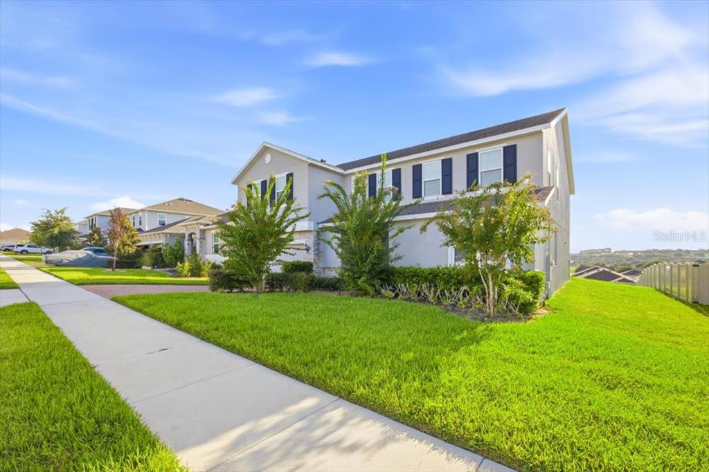 A two-story suburban house with a light gray exterior, dark shutters, and a front lawn — 585 STERLING RESERVE WAY, MINNEOLA, FL