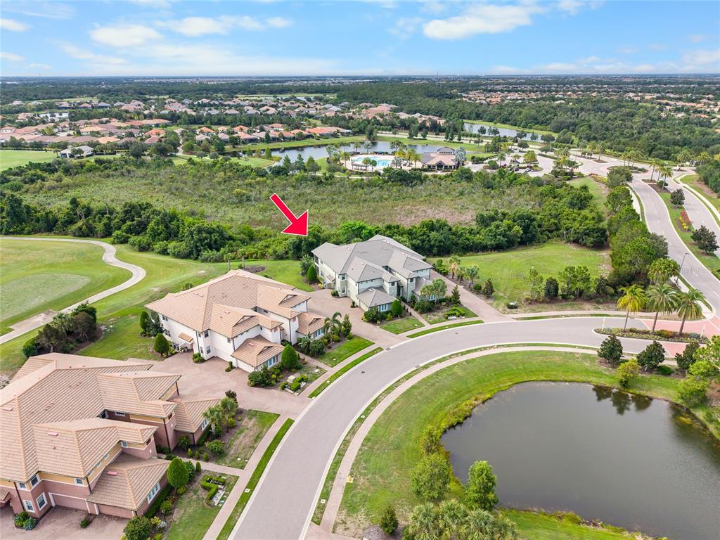An aerial view shows several large houses situated near a pond and wooded area — 7342 DIVOT LOOP, LAKEWOOD RANCH, FL