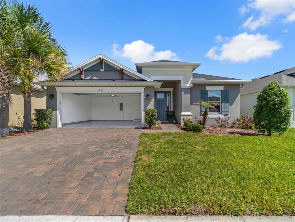 A single-story house with a paved driveway, open garage, and a gray exterior — 2632 PINNACLE LANE, CLERMONT, FL