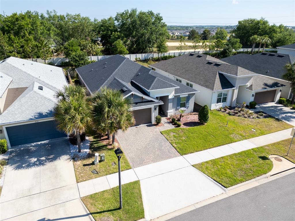 An aerial view shows three suburban houses with paved driveways and manicured lawns — 2632 PINNACLE LANE, CLERMONT, FL