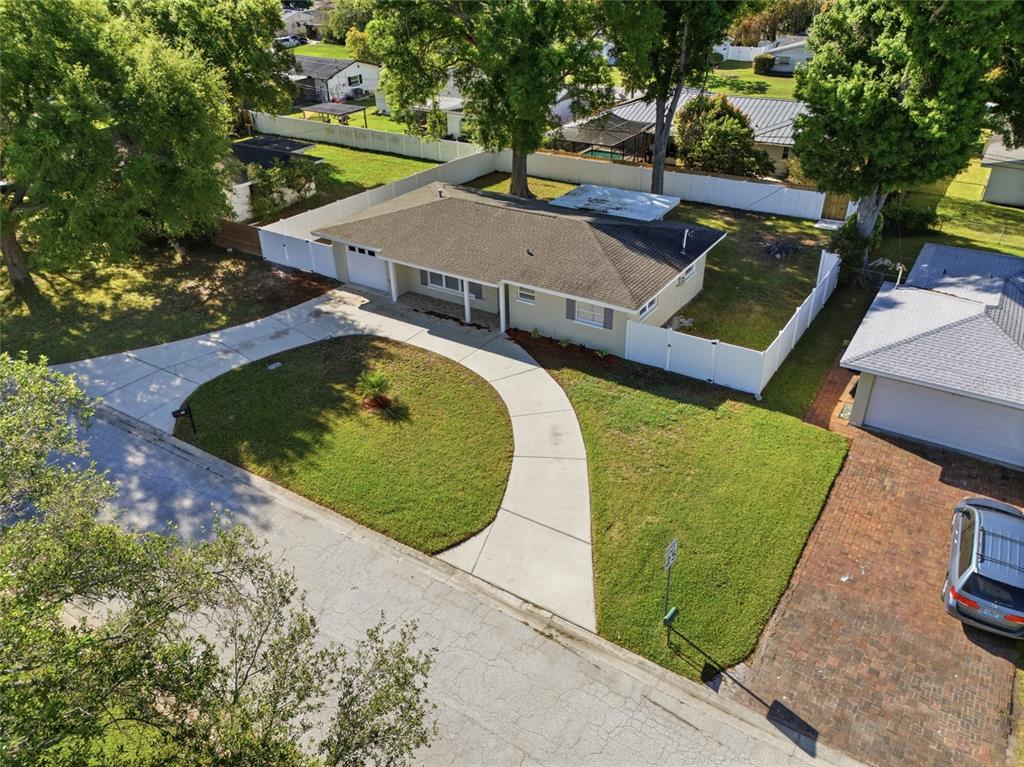 A single-story house with a white garage door, concrete driveway, and a white privacy fence — 1817 HUNT LANE, CLEARWATER, FL
