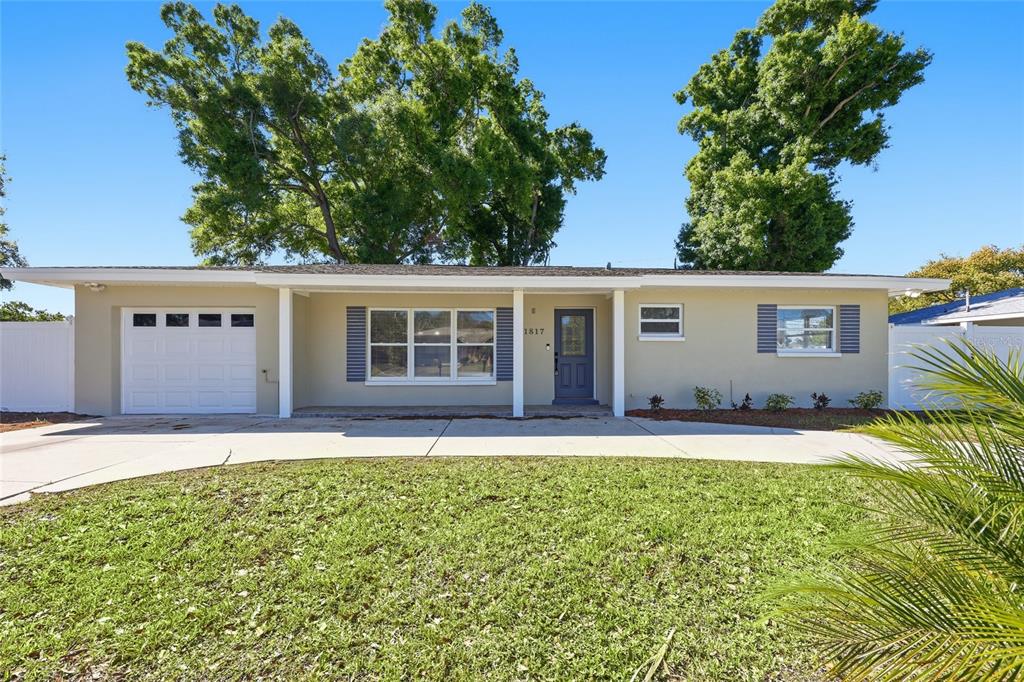 A covered porch with tiled flooring leads to a blue front door with a window — 1817 HUNT LANE, CLEARWATER, FL