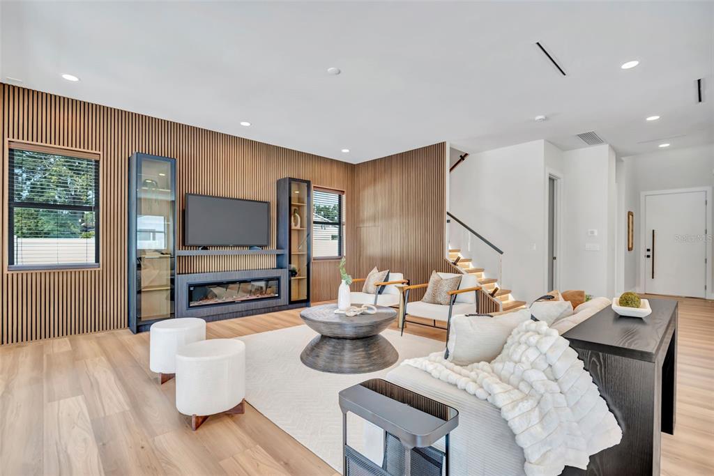 A modern living room features wood slat walls, a fireplace, and a staircase with lighting — 2112 W FARWELL DRIVE, TAMPA, FL