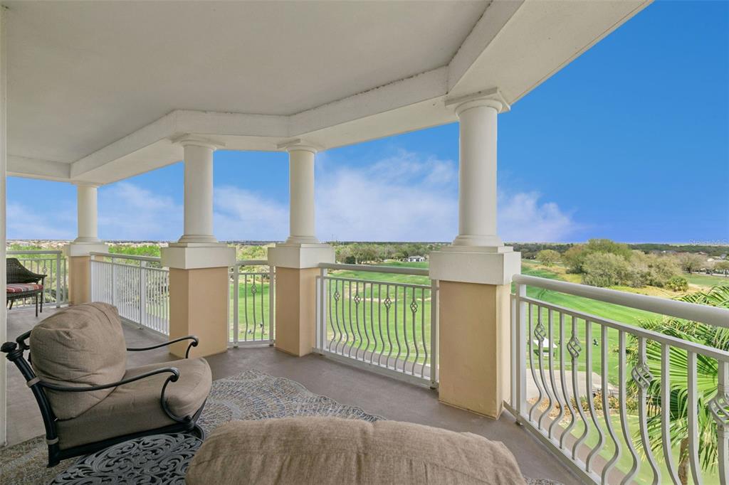 A covered balcony with columns overlooks a green golf course under a clear blue sky — 7593 GATHERING DRIVE UNIT 401, REUNION, FL