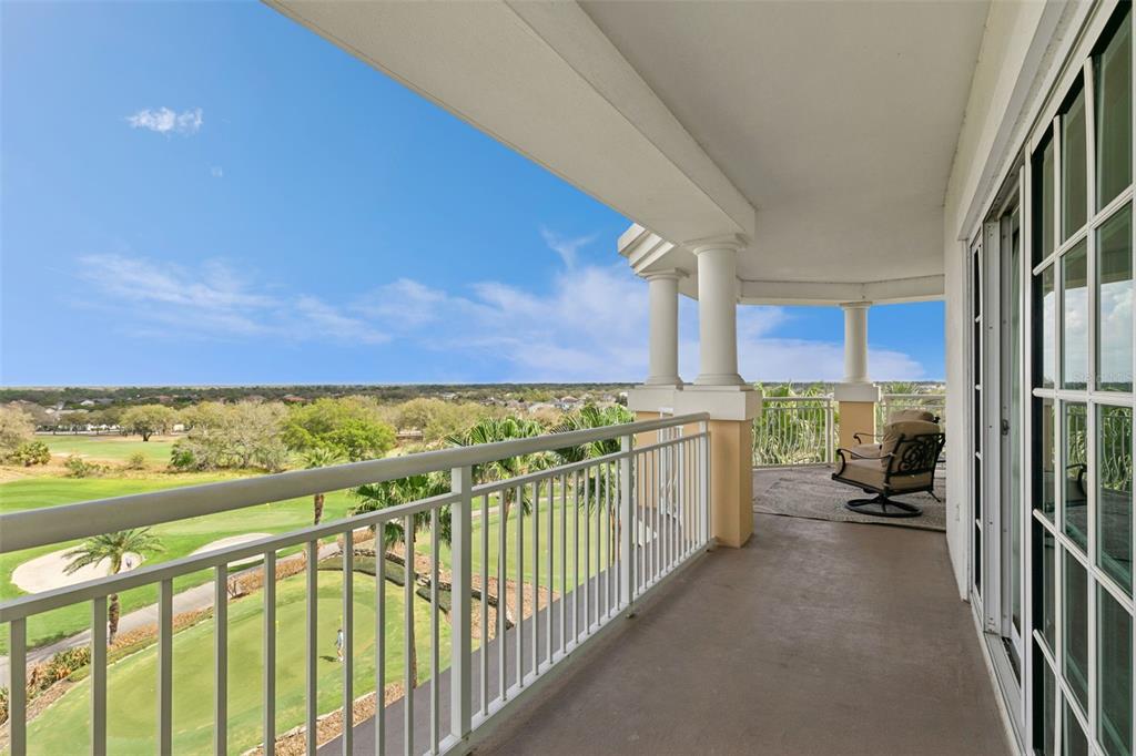 A covered balcony overlooks a golf course with white railings and columns — 7593 GATHERING DRIVE UNIT 401, REUNION, FL