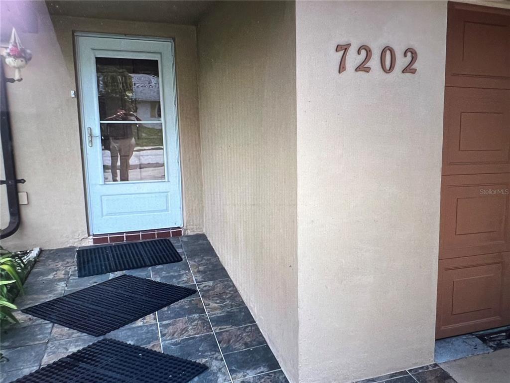 A room with gray wood-look flooring, two built-in wooden bookshelves, and a sliding glass door — 7202 GULF HIGHLANDS DRIVE, PORT RICHEY, FL