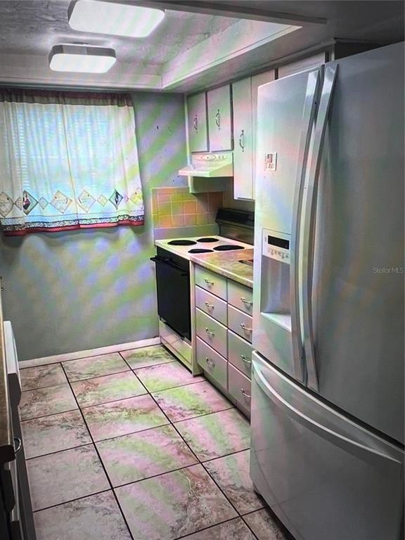 A kitchen features light gray cabinets, a tan laminate countertop, a double sink, and tiled flooring — 7202 GULF HIGHLANDS DRIVE, PORT RICHEY, FL