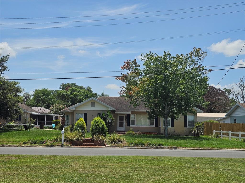A single-story house with a tan exterior, a front yard, and a large tree — 706 AVENUE I NE, WINTER HAVEN, FL