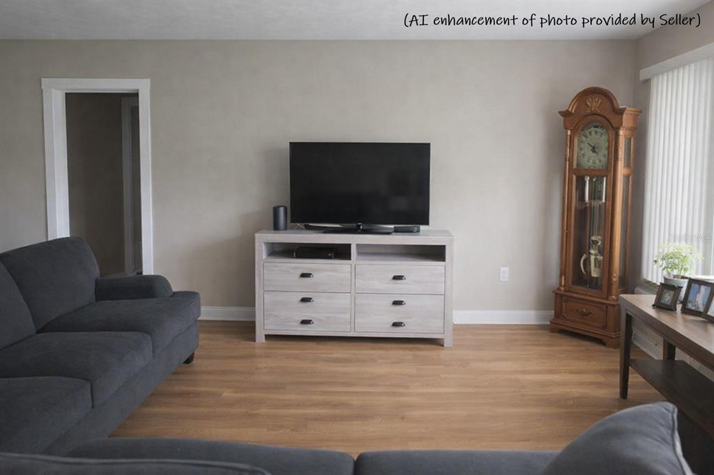 A living room features a television on a light wood console, a sofa, and a clock — 706 AVENUE I NE, WINTER HAVEN, FL