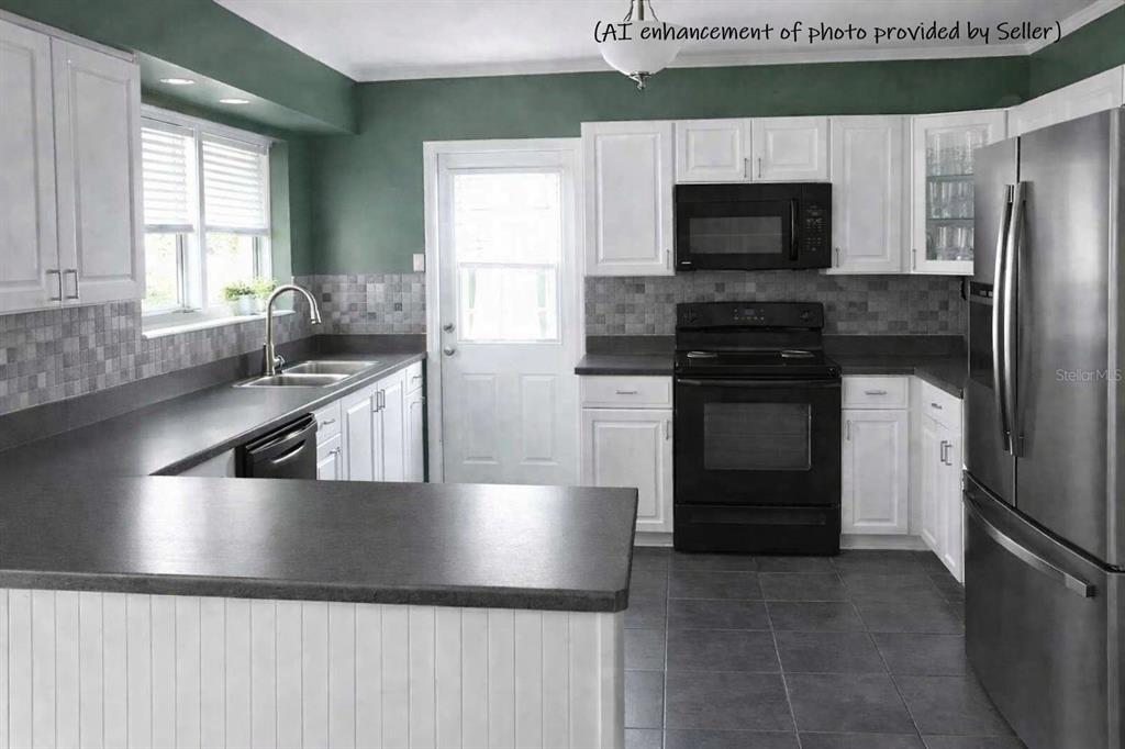 This kitchen features white cabinets, dark countertops, black appliances, and green walls — 706 AVENUE I NE, WINTER HAVEN, FL