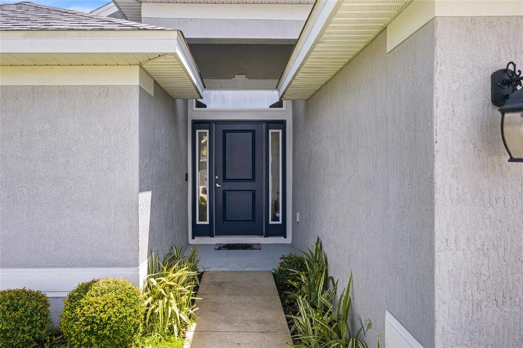 A dark blue front door with sidelights and a transom window at a home entrance — 4427 NW 2ND COURT, OCALA, FL