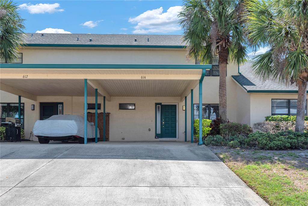 A two-story residential building features a shared carport with two entry doors and a driveway — 614 YARDARM DRIVE UNIT 7, APOLLO BEACH, FL