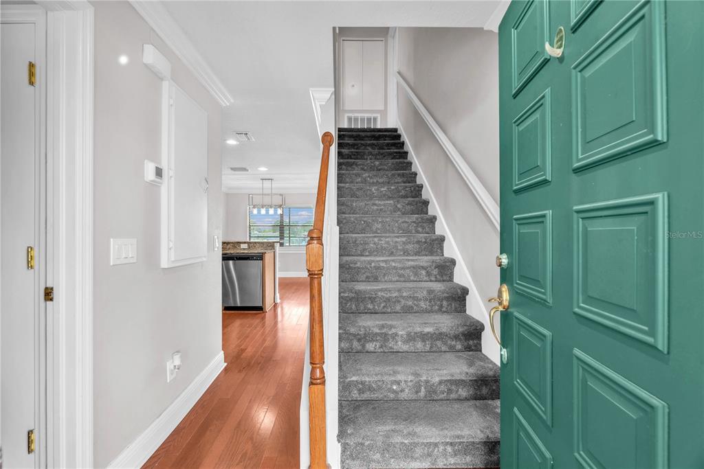 An entryway features a teal front door, carpeted stairs, and a view into a kitchen — 614 YARDARM DRIVE UNIT 7, APOLLO BEACH, FL