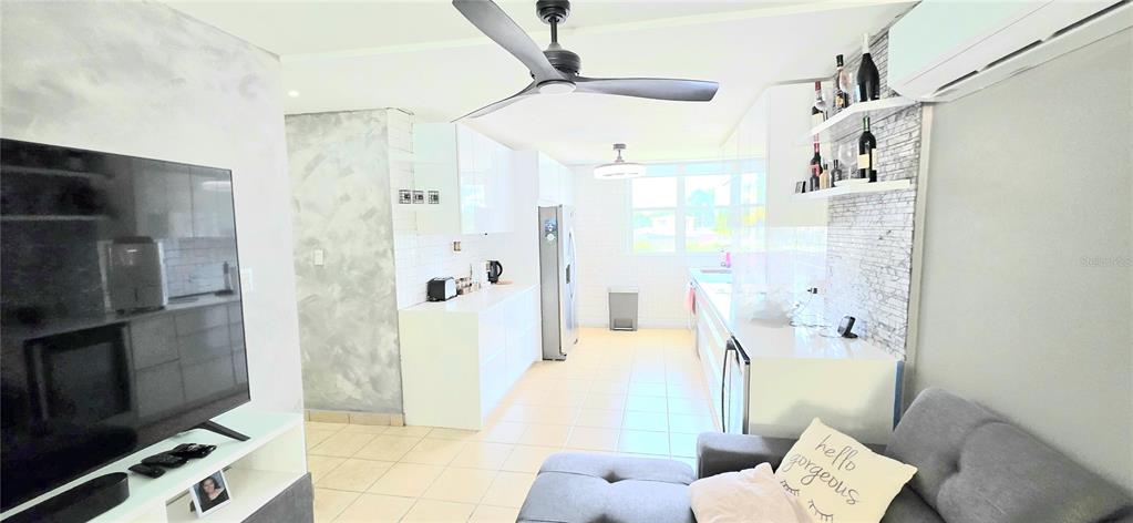This open-concept living area features a modern kitchen, white cabinetry, tile flooring, and a ceiling fan — Carr. 187 KM 23.6 AQUATIKA A-8 UNIT 1601, LOIZA, PR