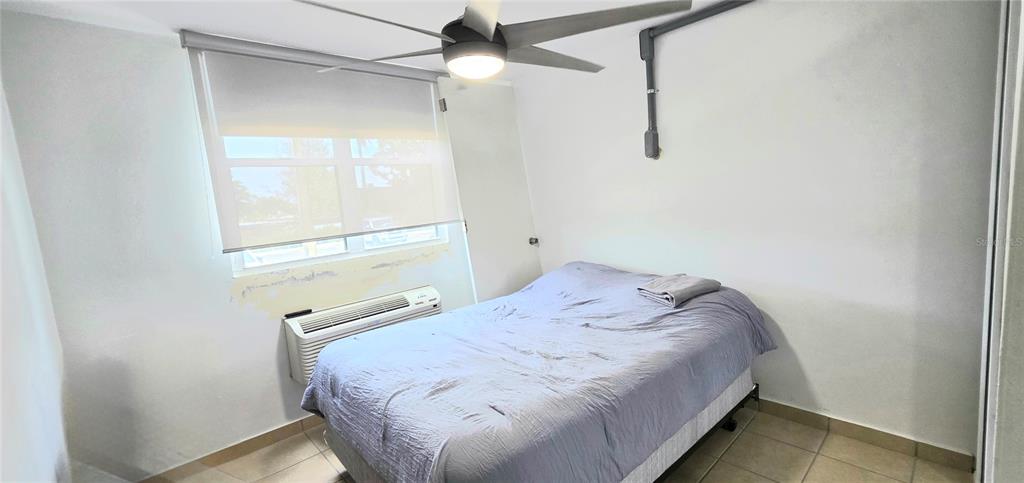 A bedroom features a bed, a ceiling fan, a window with a shade, and tile flooring — Carr. 187 KM 23.6 AQUATIKA A-8 UNIT 1601, LOIZA, PR