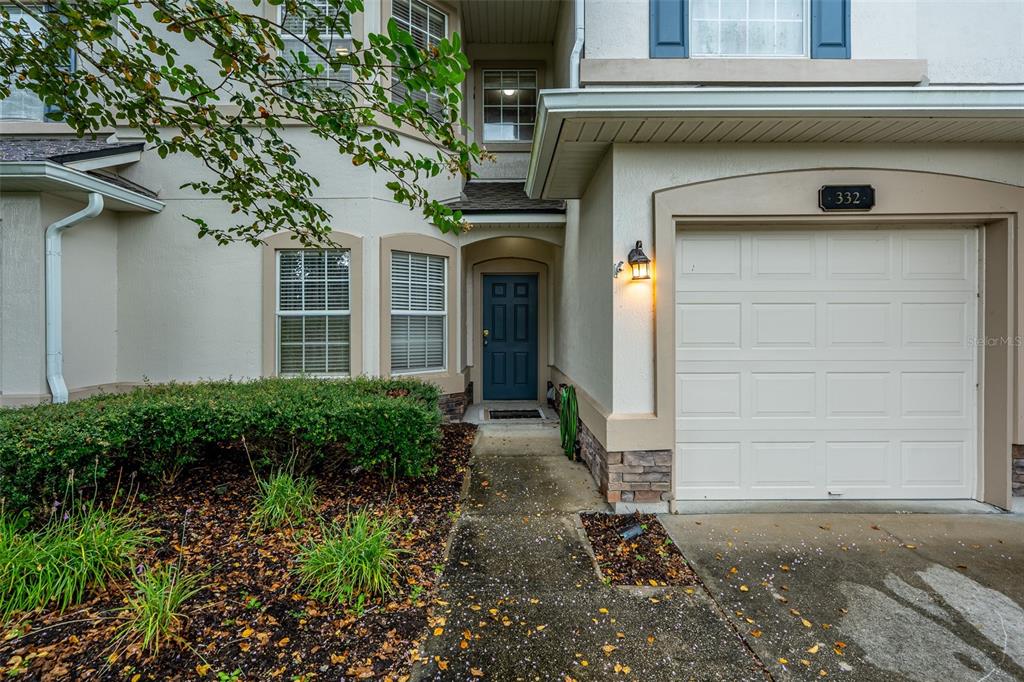 A two-story townhouse features a beige exterior, a single-car garage, and a front lawn — 332 WOODED CROSSING CIRCLE, ST AUGUSTINE, FL