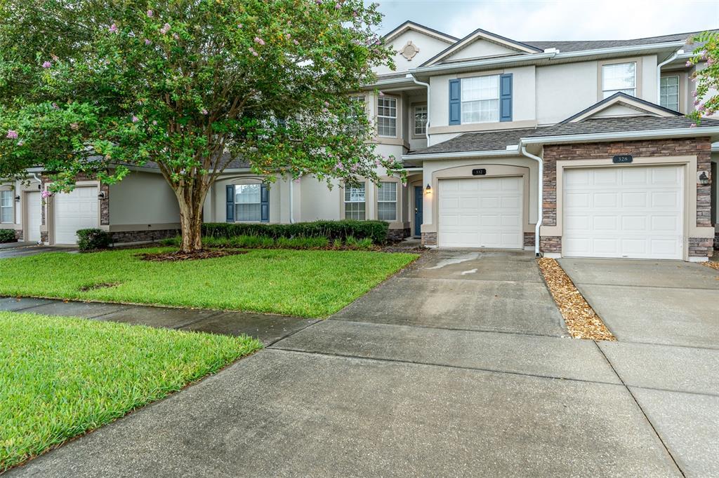 An exterior view of a multi-unit townhouse complex with attached garages and a shared driveway — 332 WOODED CROSSING CIRCLE, ST AUGUSTINE, FL
