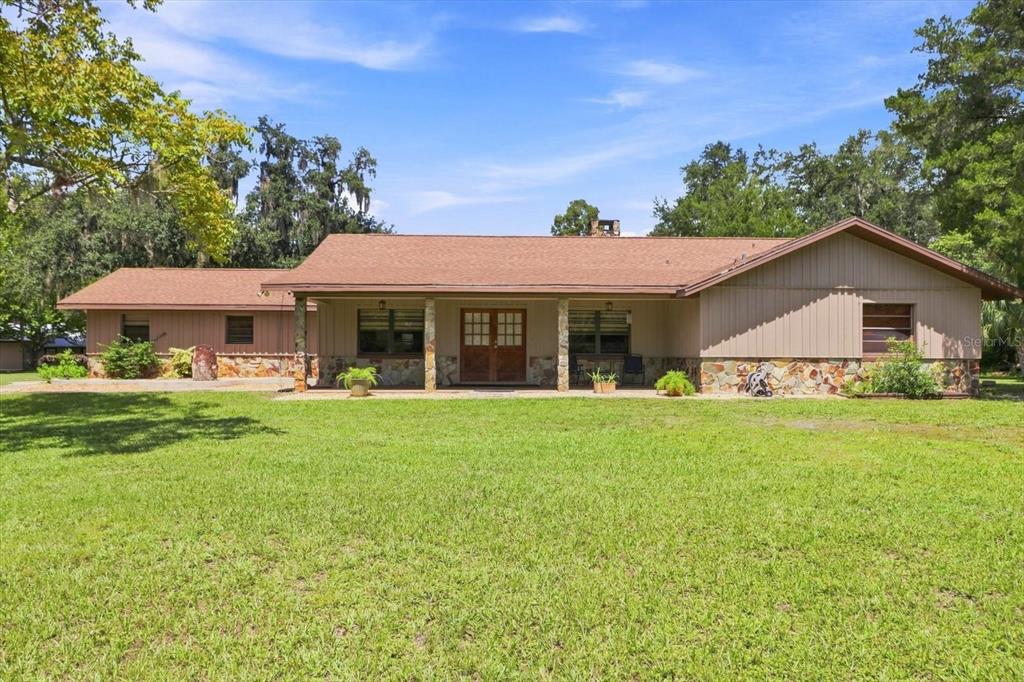A single-story house with a brown roof, vertical siding, and a stone-accented front porch — 10265 W SPRINGTREE LANE, CRYSTAL RIVER, FL