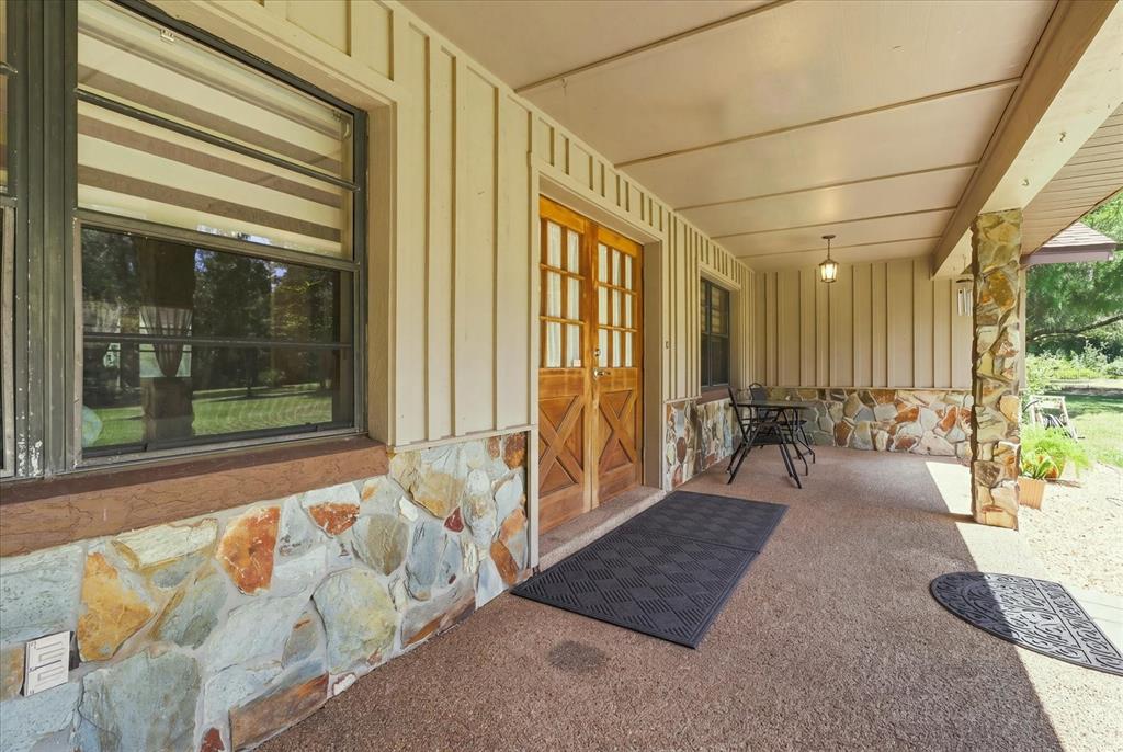 A covered porch features stone siding, vertical wood paneling, and a double wooden front door — 10265 W SPRINGTREE LANE, CRYSTAL RIVER, FL