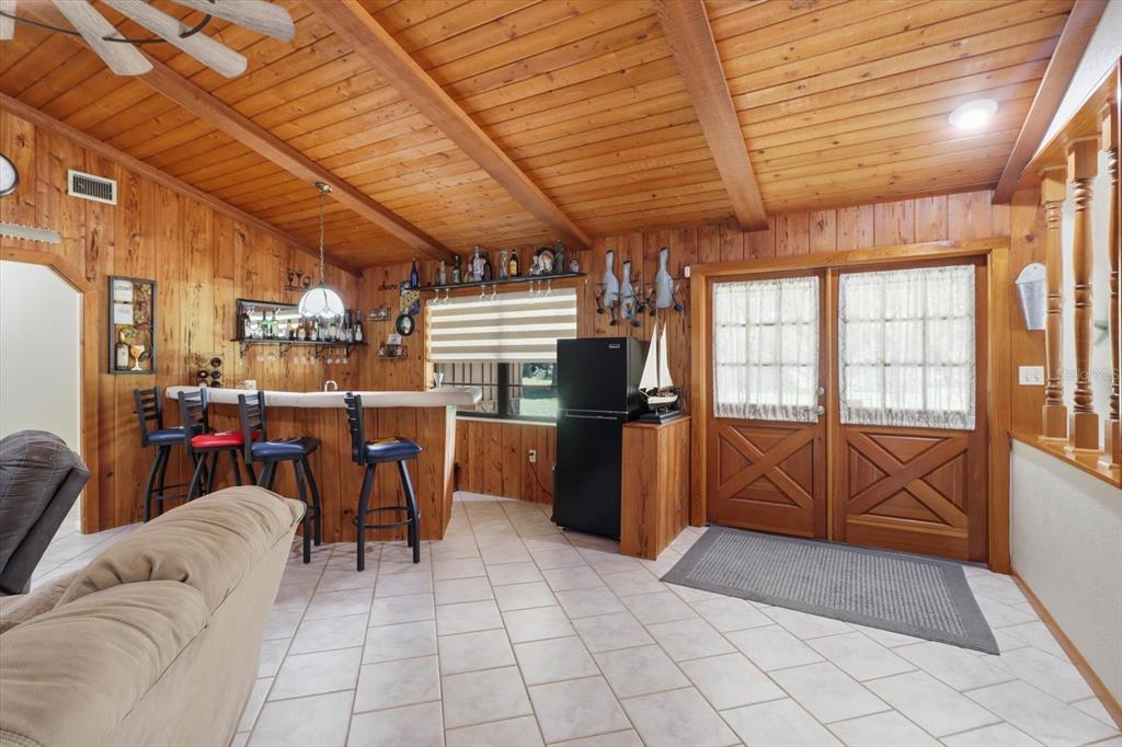 A wood-paneled room features a home bar, tile flooring, and double doors with curtains — 10265 W SPRINGTREE LANE, CRYSTAL RIVER, FL