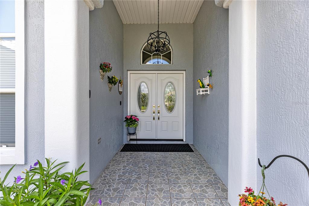 A covered entryway features a double front door with glass inserts and tiled flooring — 6744 SW 113TH PLACE, OCALA, FL