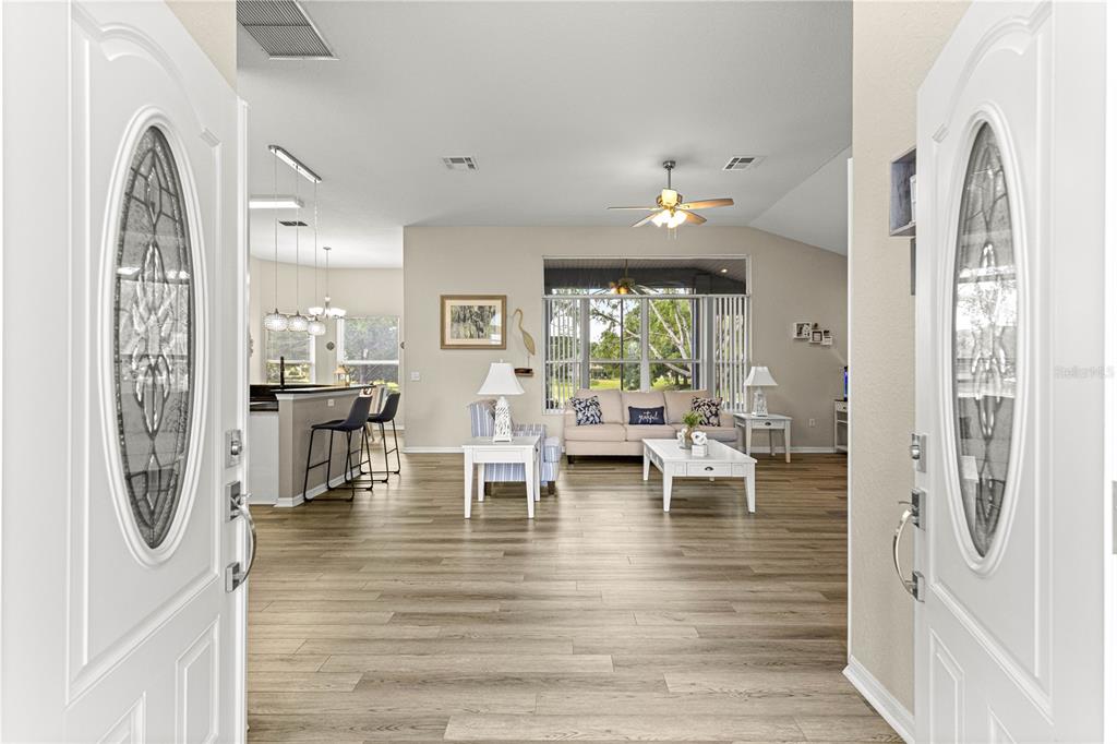A view from an entryway into a living room with wood-look floors and a kitchen — 6744 SW 113TH PLACE, OCALA, FL