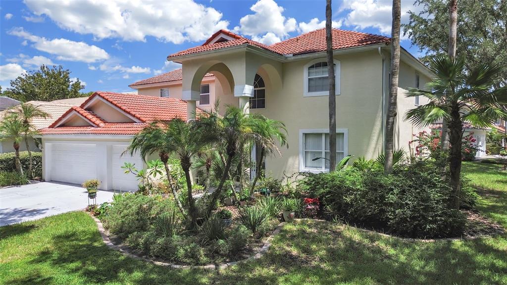 A two-story house with a red tile roof, arched entryway, and a landscaped front yard — 10212 GARDEN ALCOVE DRIVE, TAMPA, FL