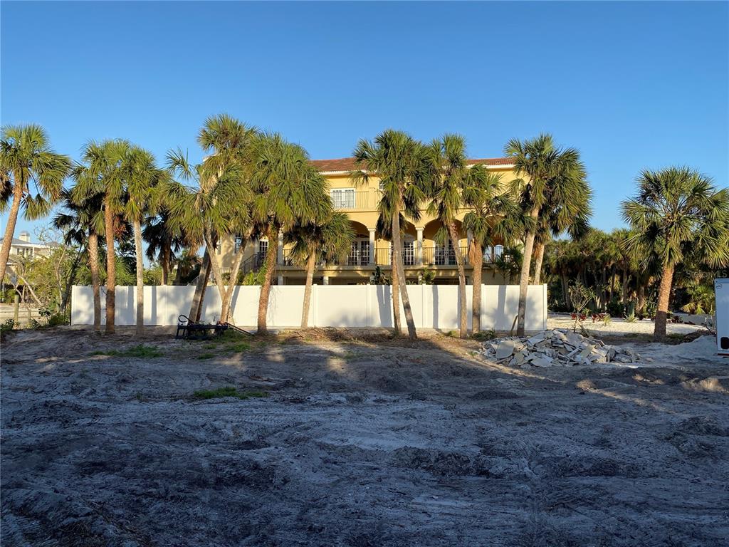 A large yellow multi-story house stands behind a white fence and several palm trees — 61 PALM DRIVE, PLACIDA, FL