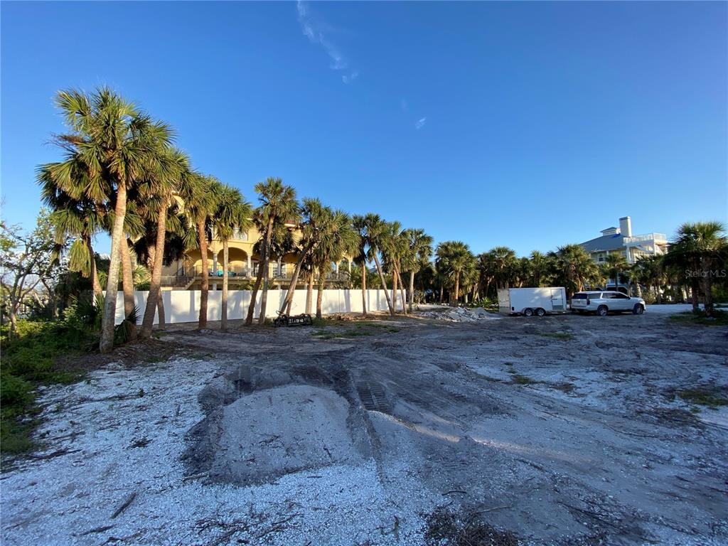 A vacant, sandy lot features a row of palm trees and a white fence — 61 PALM DRIVE, PLACIDA, FL