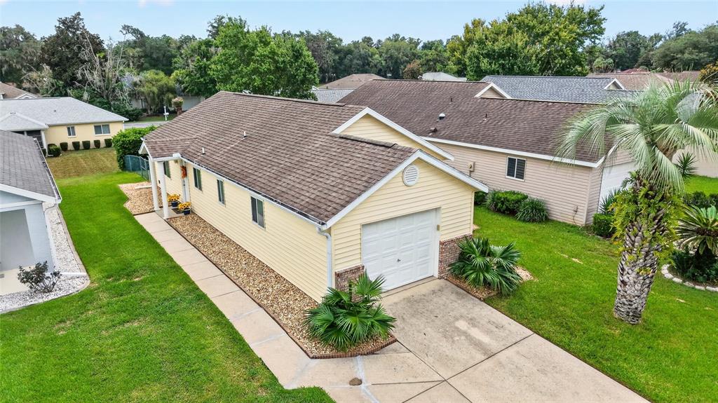 A light yellow house with a white garage door and a palm tree in front — 1921 NW 50TH CIRCLE, OCALA, FL