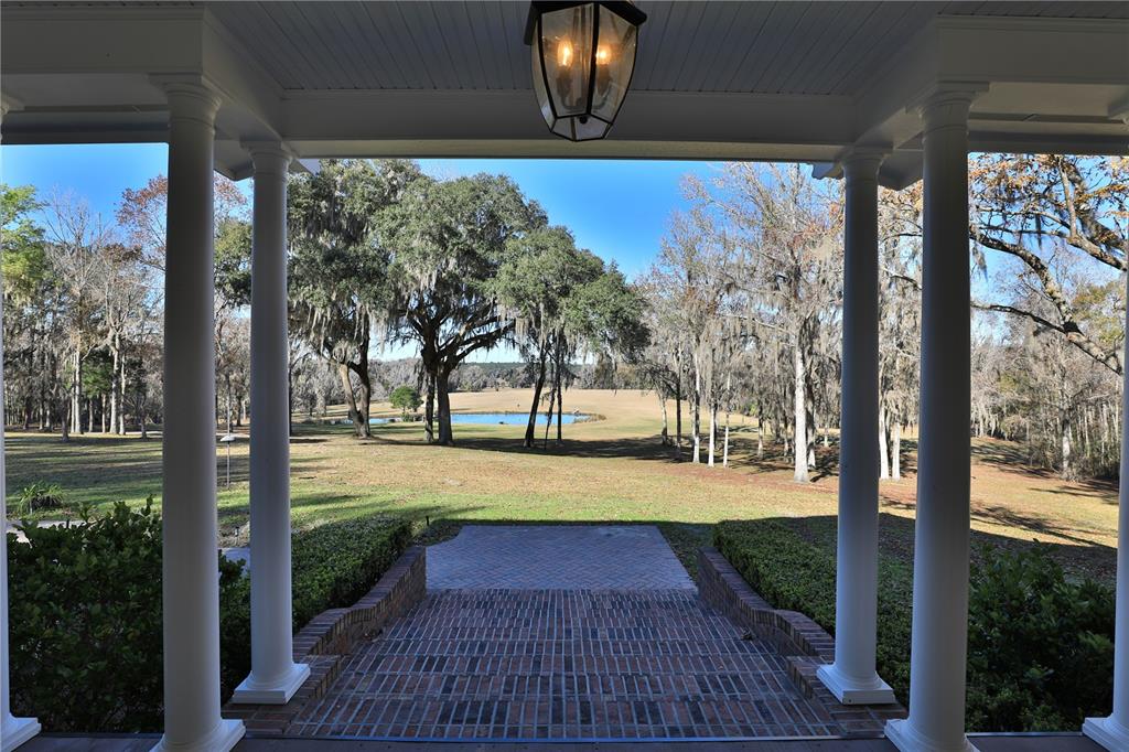 A view from a covered porch with white columns looking out over a grassy lawn — 15551 NW HIGHWAY 225, REDDICK, FL