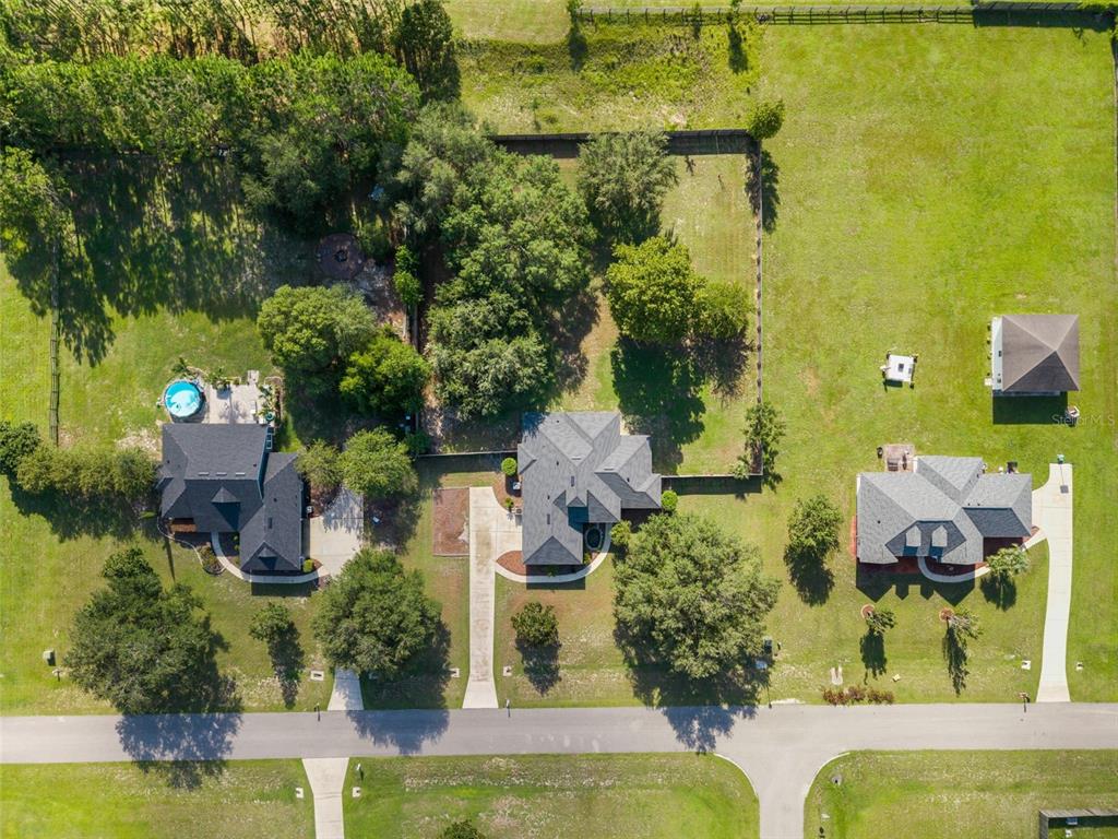 An aerial view shows three houses with driveways and lawns in a suburban neighborhood — 9978 SW 98TH TERRACE, GAINESVILLE, FL