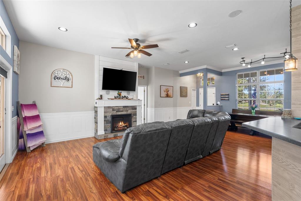 A living room features a stone fireplace, a grey sectional sofa, and hardwood flooring — 9978 SW 98TH TERRACE, GAINESVILLE, FL