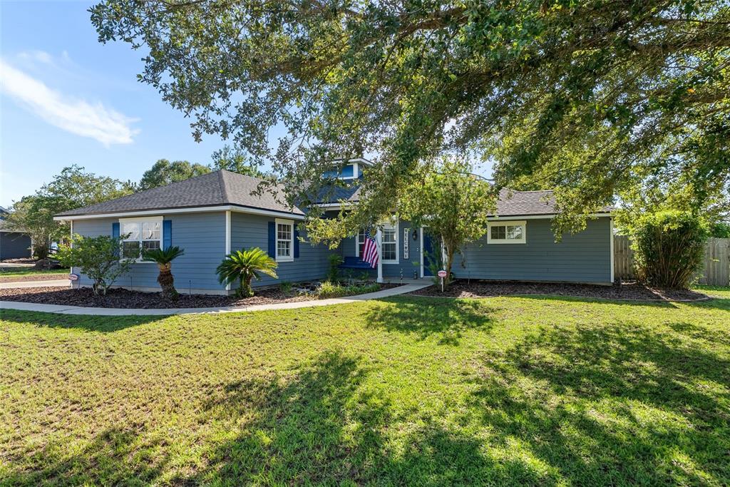 A blue, single-story house with a dark shingled roof, white trim, and a front lawn — 9978 SW 98TH TERRACE, GAINESVILLE, FL