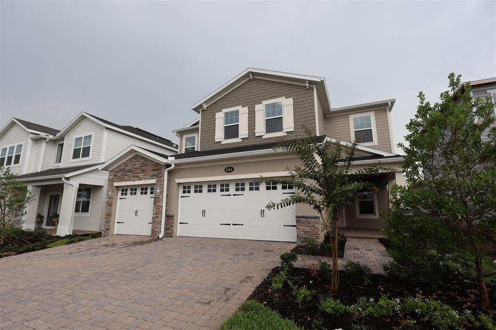 A modern kitchen features wood cabinets, a large white island, and light-colored tile flooring — 1314 HYDE STREET, ST CLOUD, FL
